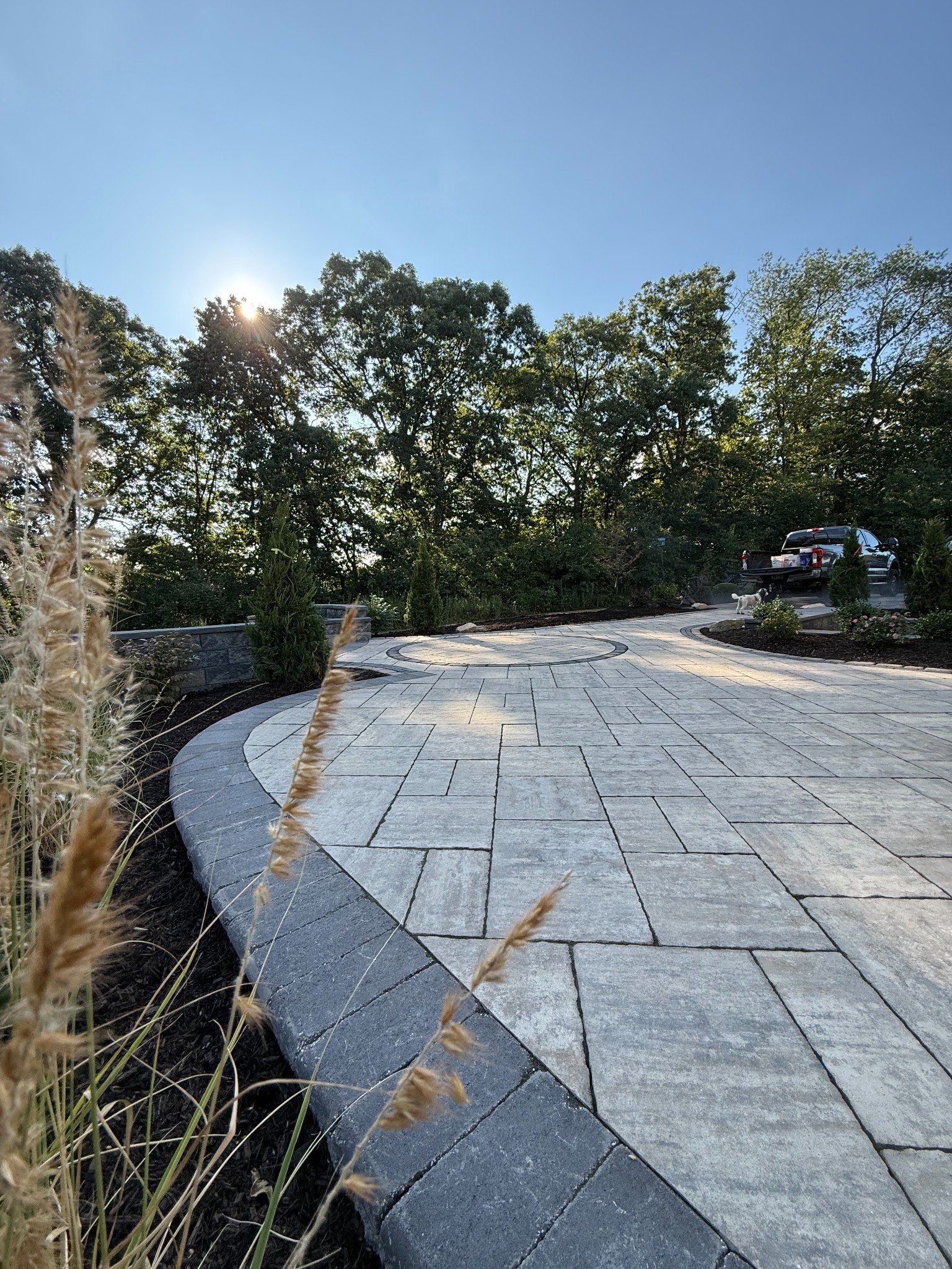 Large custom paver patio and landscaped outdoor living space by Elevated Landscaping
